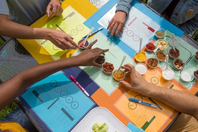 Plusieurs personnes jouent à un jeu sur la dégustation de nourriture à l'aide d'un stylo et d'une carte colorée