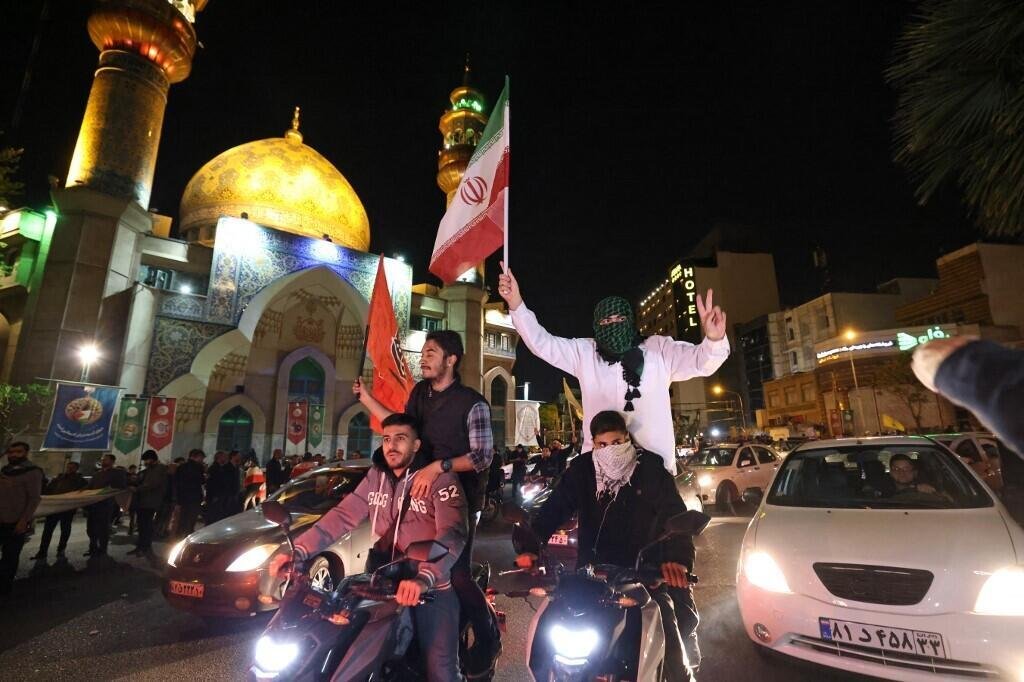Des manifestants brandissent le drapeau iranien et des drapeaux palestiniens alors qu'ils se rassemblent sur la place de la Palestine à Téhéran le 14 avril 2024, après que l'Iran a lancé une attaque de drones et de missiles sur Israël.