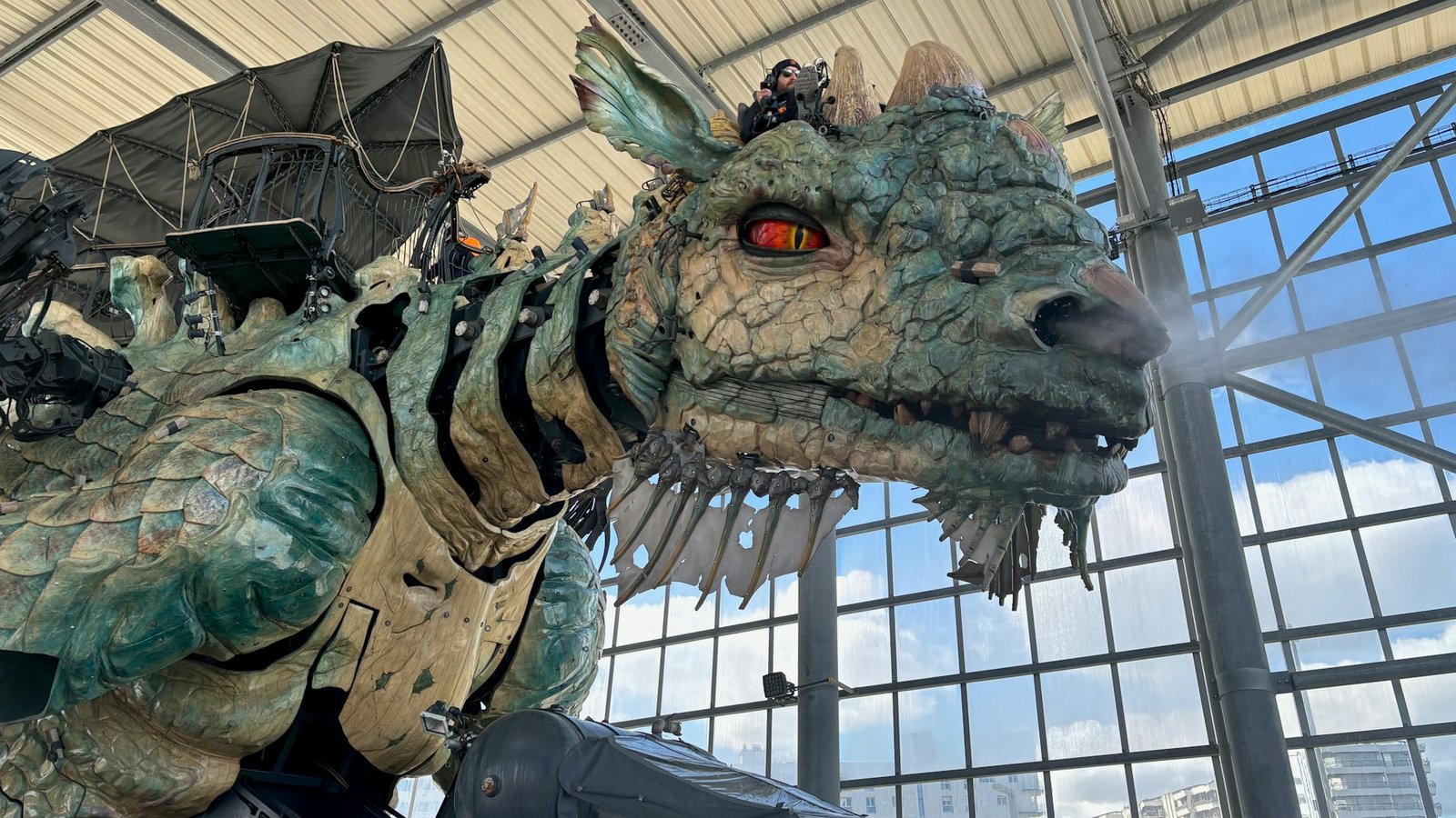 Un énorme dragon mécanique, contrôlé par un pilote à l'aide de niveaux et de pédales, trône dans son hangar transparent