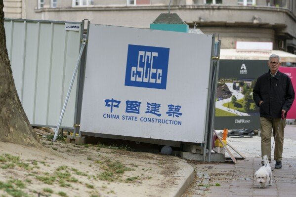 Un homme avec un chien se promène près d'un chantier de construction à Belgrade, en Serbie, le mercredi 1er mai 2024. Le président chinois Xi Jinping se rendra en France, en Serbie et en Hongrie la semaine prochaine alors que Pékin semble chercher à jouer un rôle plus important dans le conflit entre la Russie et l'Ukraine. qui a bouleversé la sécurité politique et économique mondiale.  (Photo AP/Darko Vojinovic)