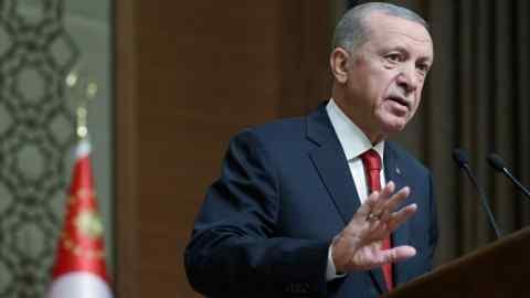 Un homme d'âge moyen en costume se tient devant un pudium