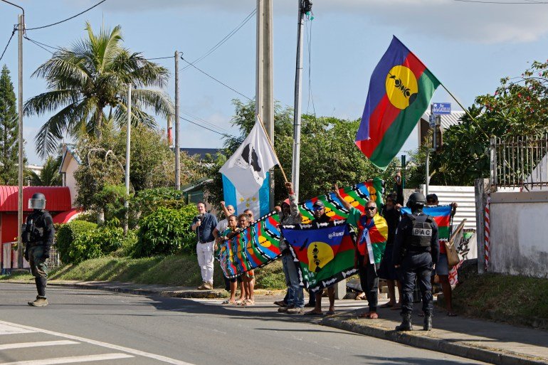 les gens tiennent des drapeaux aux couleurs vives dans une rue tropicale