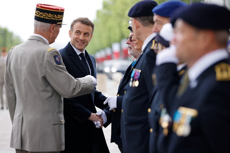 Le président français Emmanuel Macron serre la main d'anciens combattants français lors d'un défilé marquant l'anniversaire de la fin de la Seconde Guerre mondiale en Europe.