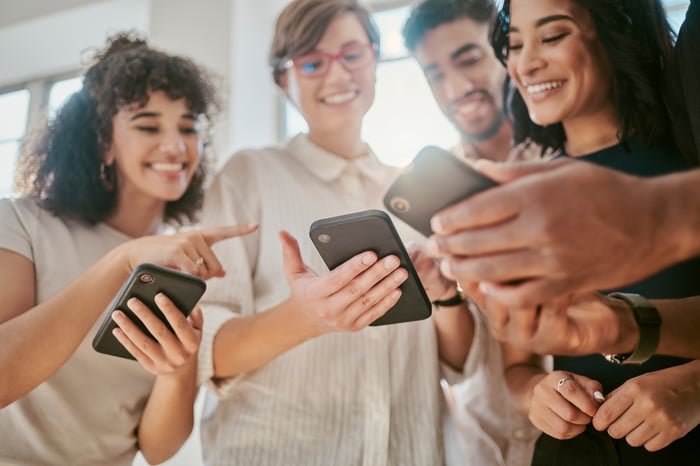 Groupe de jeunes souriants avec des téléphones portables.