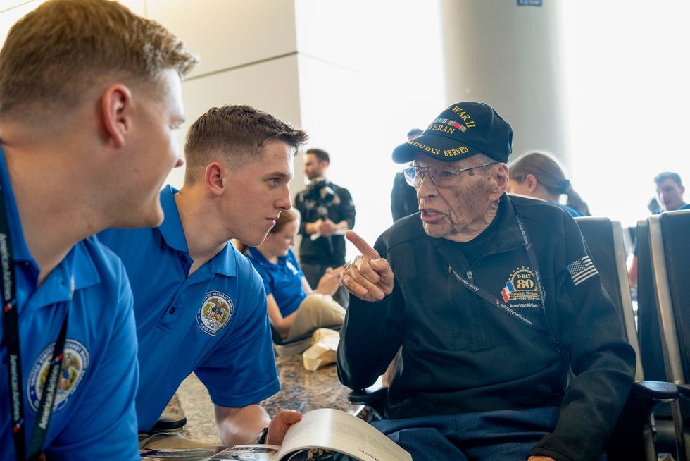 Veteran Sydney Sid Edson sits with United States Air Force Academy Students at the airline gate before a flight from Dallas to France on May 31, 2024.