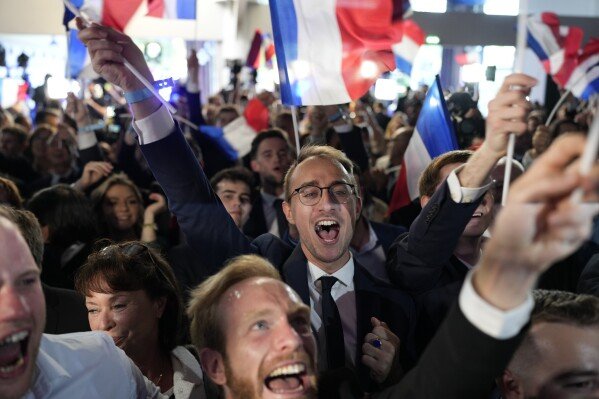 Les partisans du Rassemblement national d'extrême droite réagissent au siège du parti lors de la soirée électorale, dimanche 9 juin 2024 à Paris. Les premiers résultats projetés en France placent le parti d'extrême droite du Rassemblement national largement en tête des élections européennes, selon les instituts de sondage d'opinion français. (Photo AP/Lewis Joly)