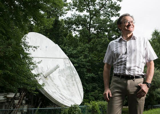 Sur cette photo, un homme, Peter Pachowicz, se tient à côté d'un plat satalitte à l'extérieur.