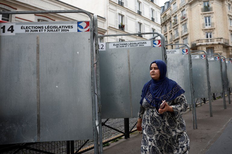 Une femme passe devant les commissions électorales placées avant les élections parlementaires françaises du 30 juin et du 7 juillet, à Paris, France, le 19 juin 2024. REUTERS/Benoit Tessier
