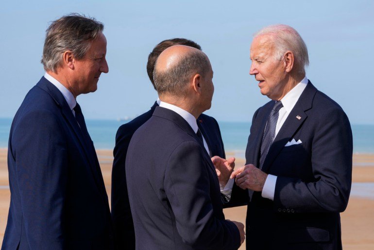 Le président américain Joe Biden, à droite, s'entretient avec le chancelier allemand Olaf Scholz, deuxième à droite, le président français Emmanuel Macron, de dos, et le ministre britannique des Affaires étrangères David Cameron, à gauche, à la fin d'une cérémonie internationale marquant le 80e anniversaire du jour J.