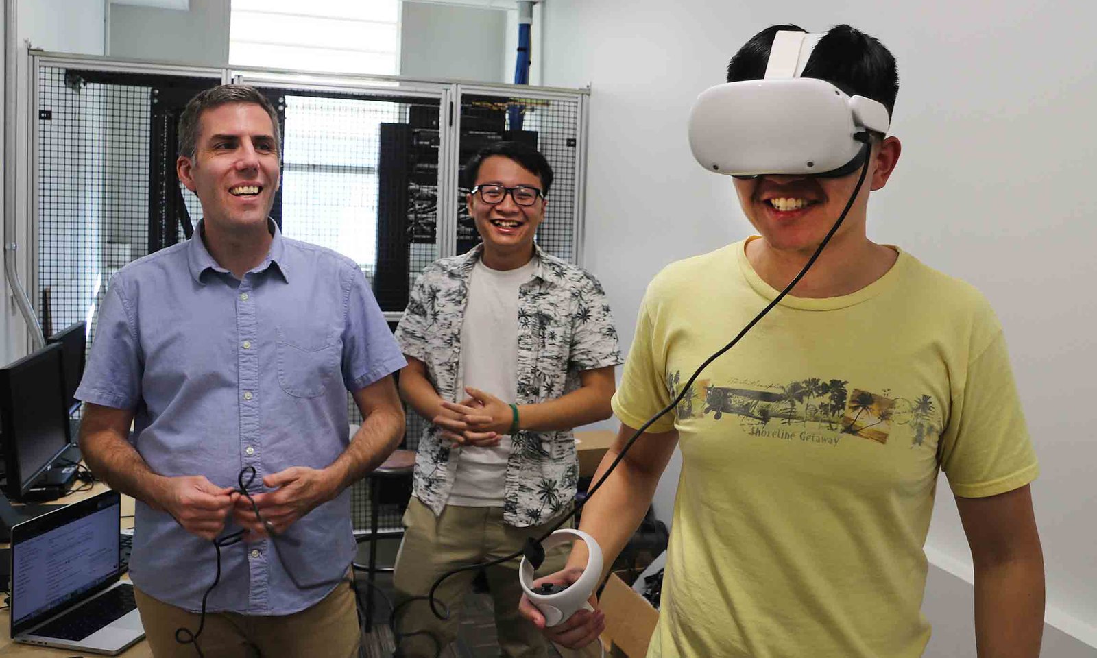 Un professeur et un étudiant regardent un autre étudiant porter un casque VR.
