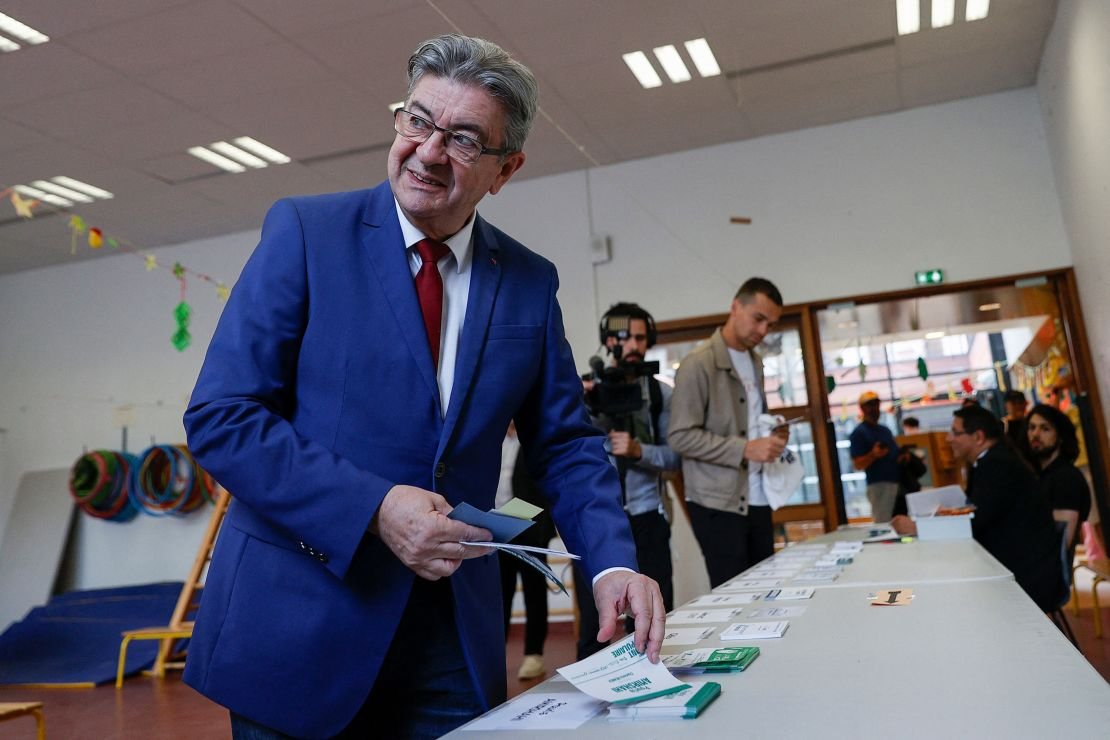 Jean-Luc Mélenchon récupère ses bulletins de vote avant de déposer son bulletin dans un bureau de vote à Paris, le 30 juin 2024.