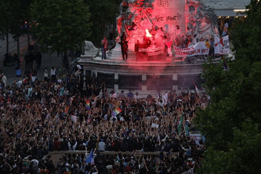 Des manifestants debout sur le Monument à la République allument des fusées éclairantes alors qu'ils participent à un rassemblement après l'annonce des résultats du premier tour des élections législatives françaises, sur la place de la République à Paris le 30 juin 2024.